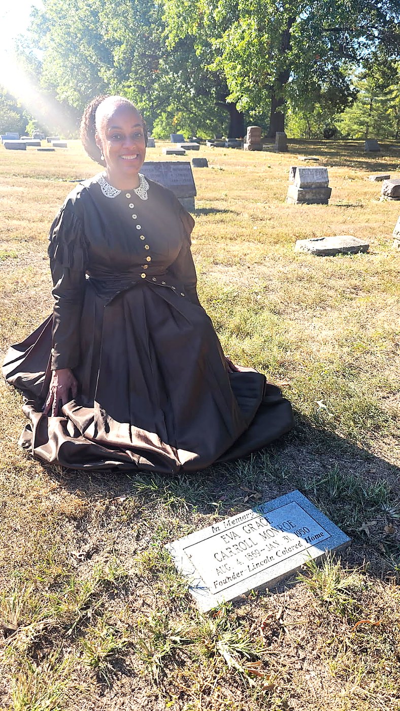 Dr. Clarissa Williams in period dress at the grave marker of Eva Grace Carroll Monroe